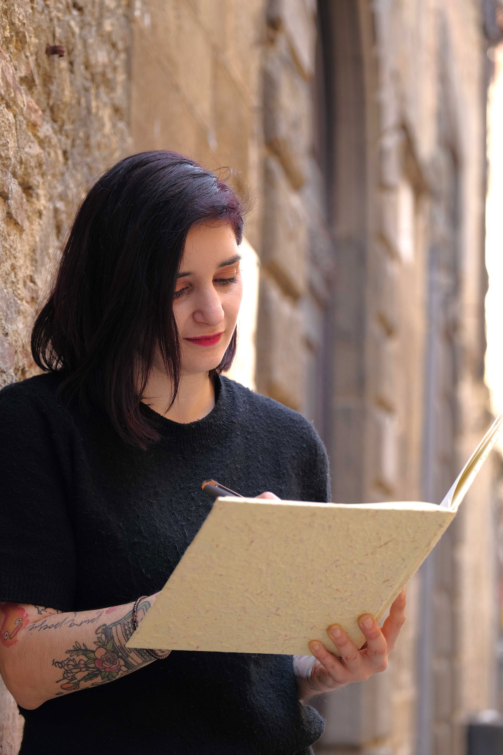 Marina Palumbo fotografata in un vicolo di pietra mentre consulta un taccuino.